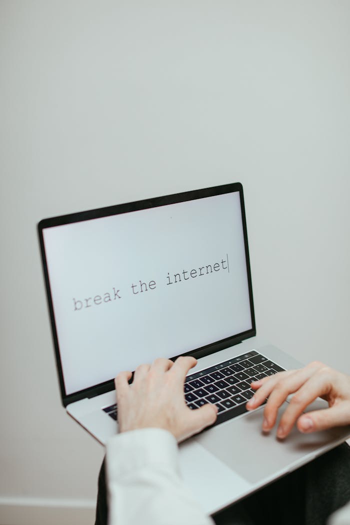 Close-up of hands typing 'break the internet' on a laptop keyboard, symbolizing creativity and digital disruption.